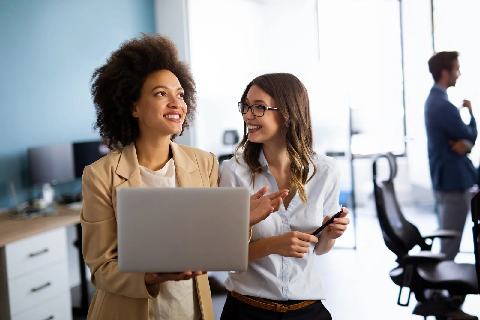 Colleagues discussing work at a laptop