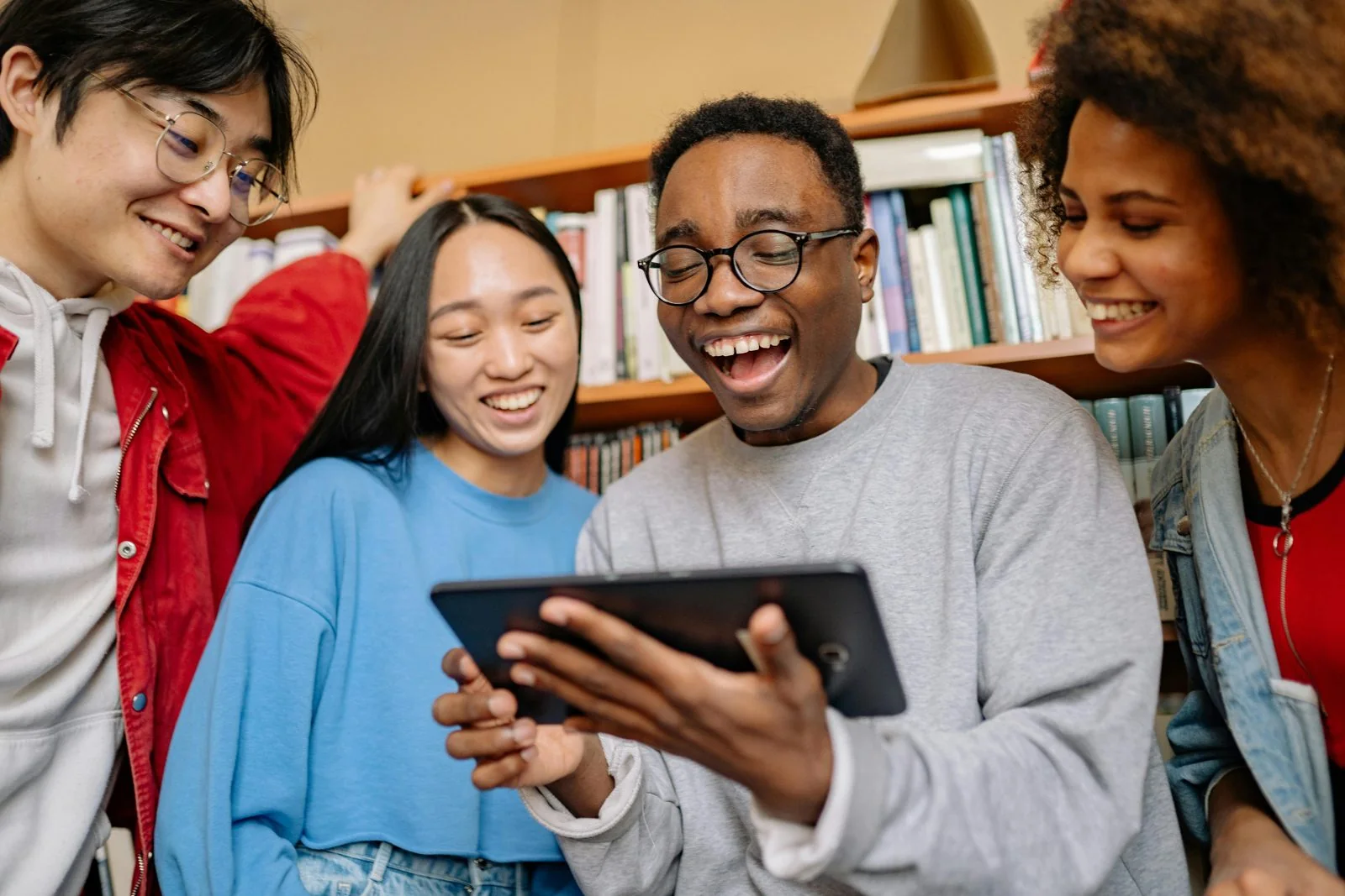 Students collaborating around a tablet in a library
